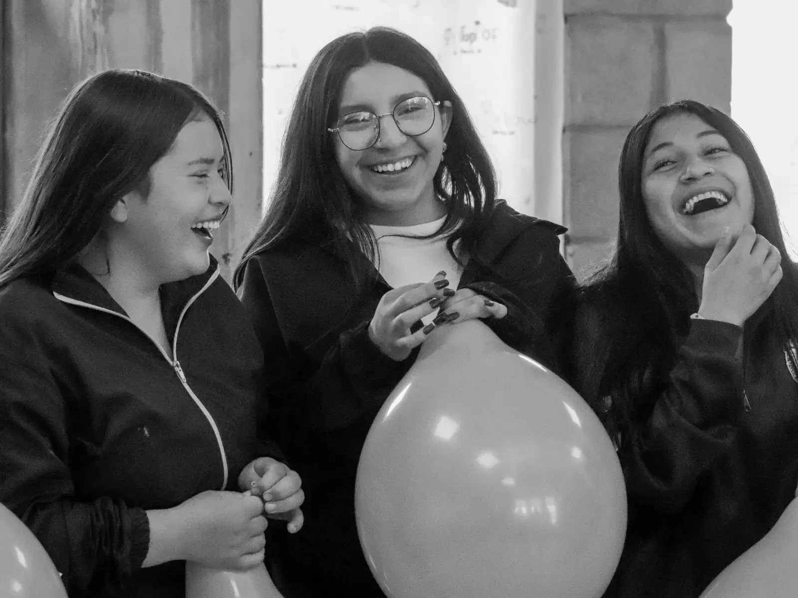 Three young women laughing together in a True Identity community space